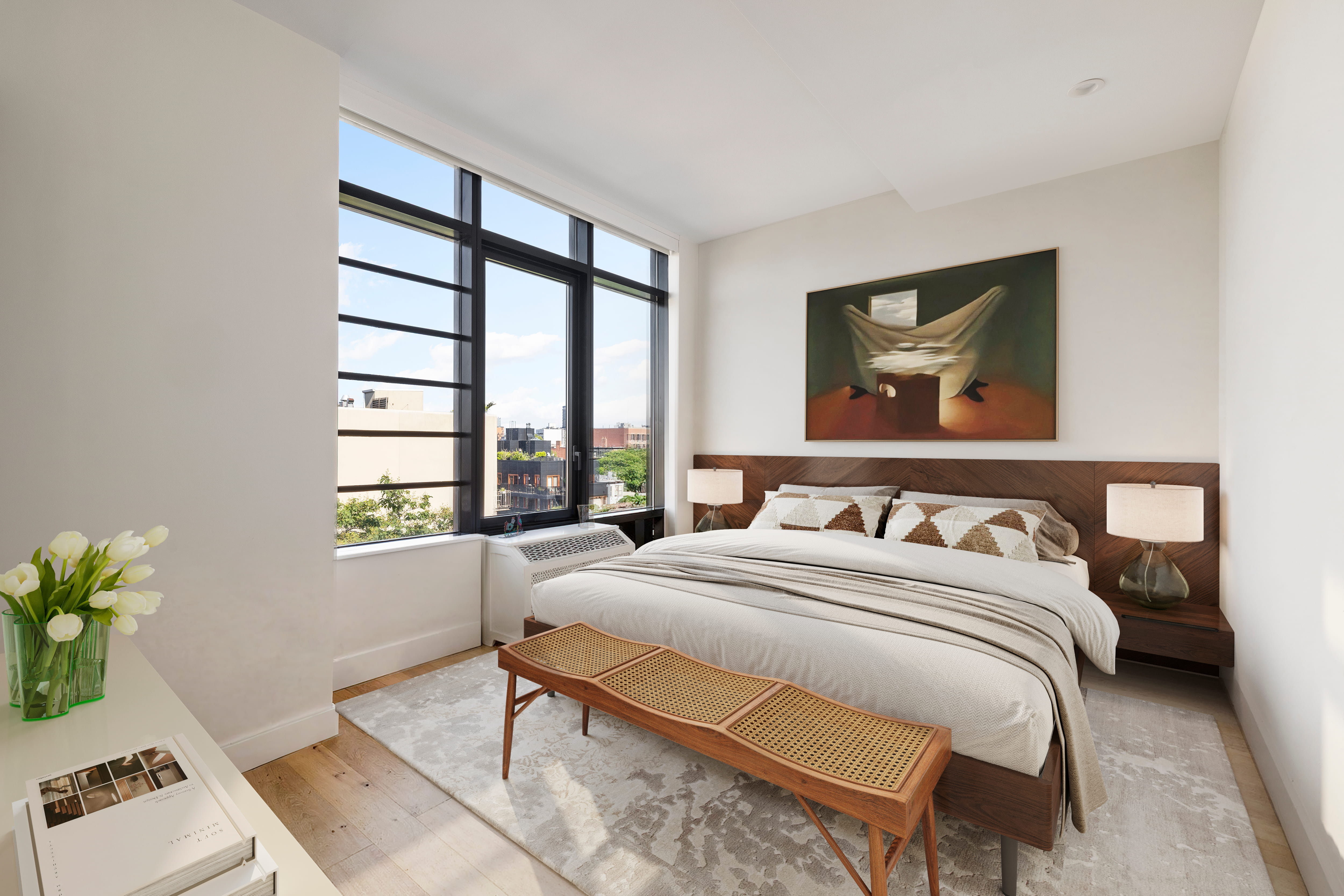 Primary bedroom with walnut headboard and city views